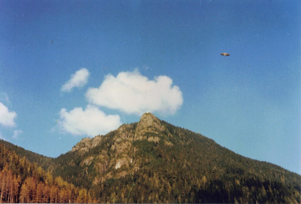 A color photograph of a disc-shaped object in the sky above a mountain, taken in 1981 on Vancouver Island, ufo photo canada, photo of ufo in canada,